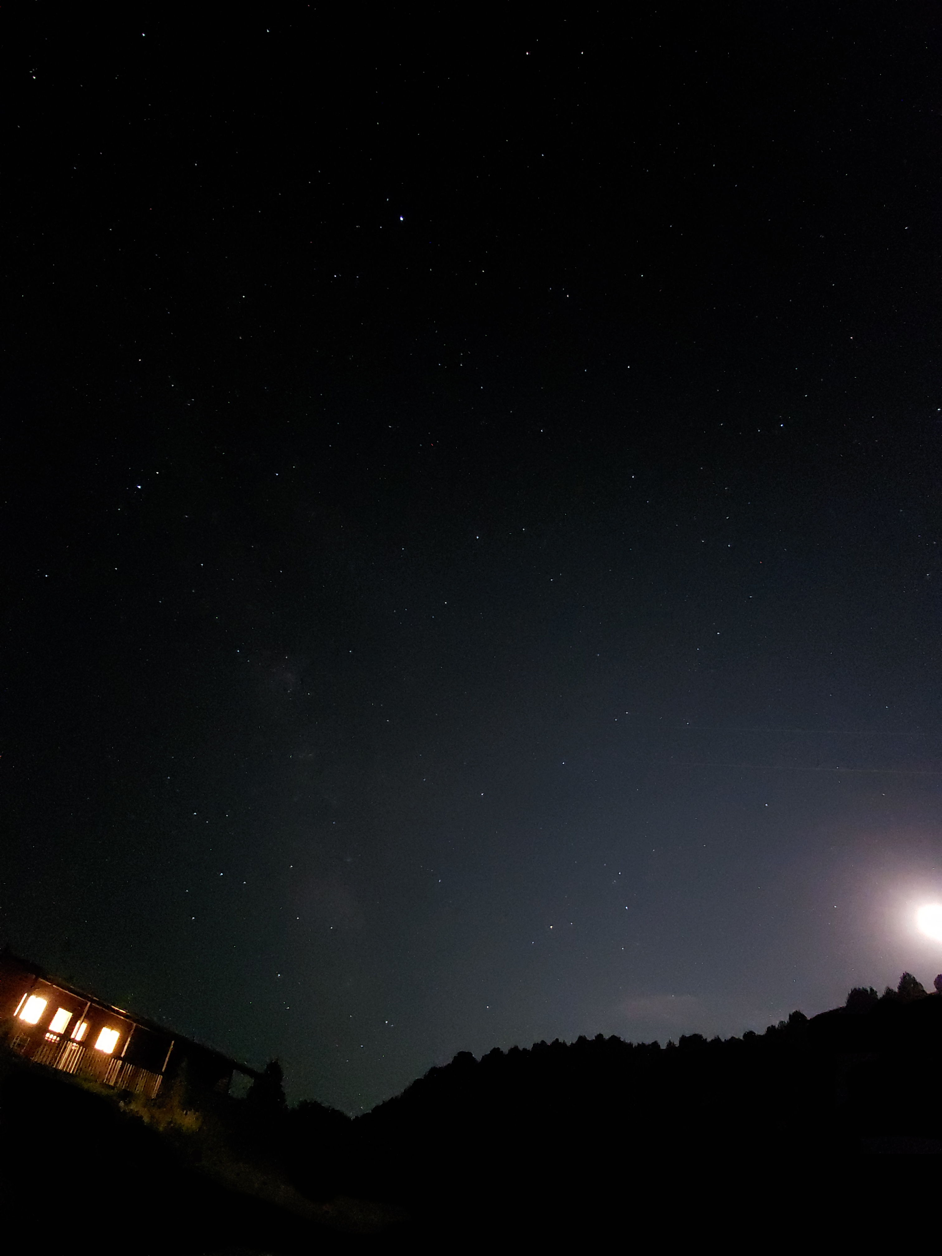 The sky with many stars and milky way, cars visible below.